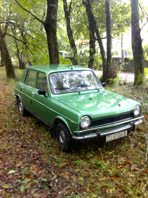 A Simca 1100 of green color parked in an oakwood