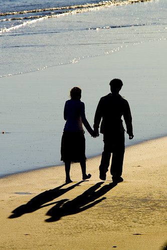 Two people walk holding hands on the beach 2-people-beach-shadows-002