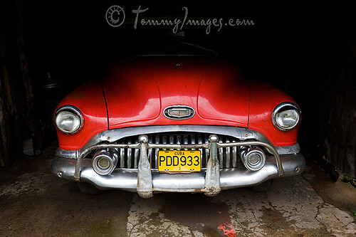 Vinales Cuba A red classic American car sits in the shadow of a garage in