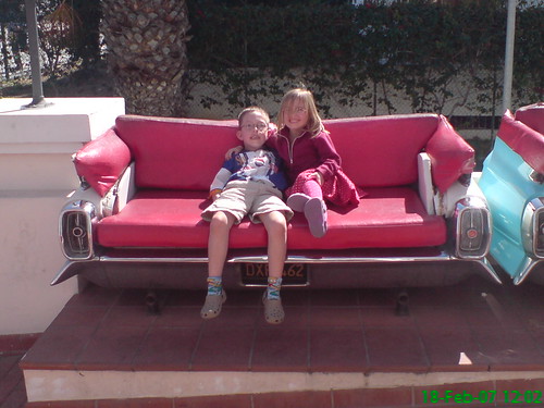 Kids travelling - sat on red outdoor sofa