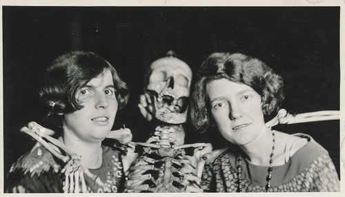 Two women pose with their skeleton friend
