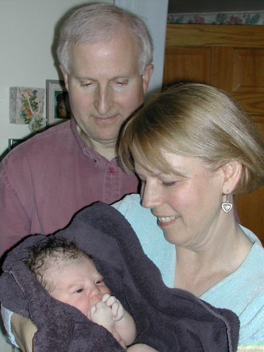 A man looking at his daughter hold her baby, depicting three generations