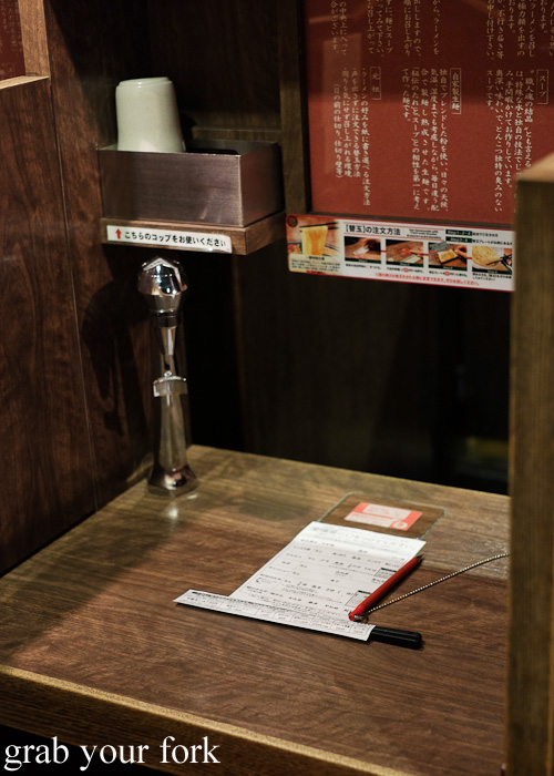 Menu and tea dispenser inside each noodle booth at Ichiran, Hakata, Fukuoka, Japan