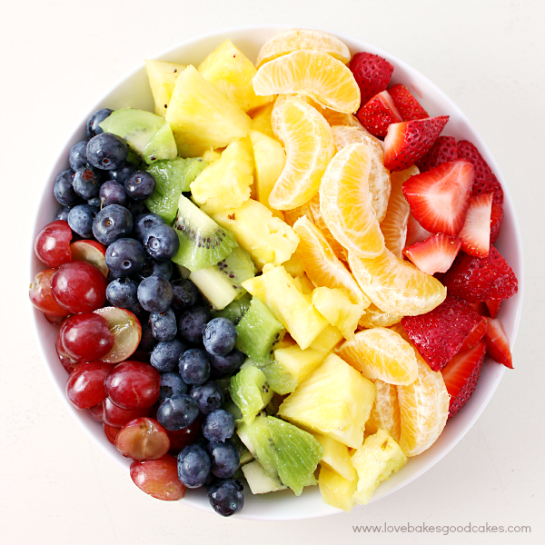 Rainbow Fruit Salad with Honey Citrus Dressing in a white bowl looking down from the top.
