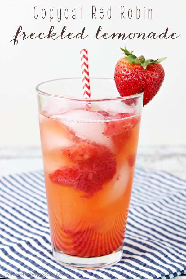 Copycat Red Robin Freckled Lemonade in a glass with a fresh strawberry and a straw.