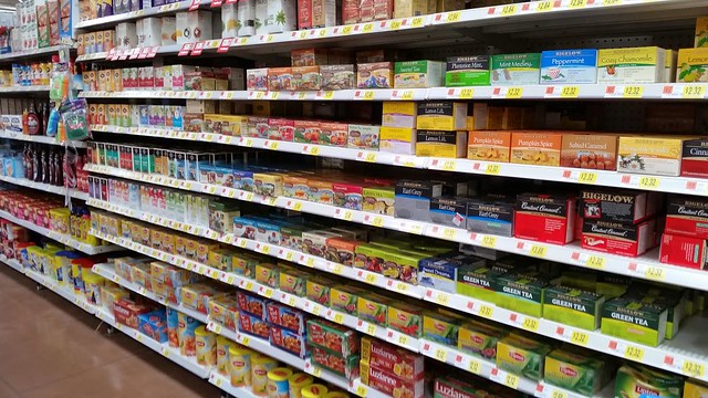 A grocery store isle with tea products on the shelves.