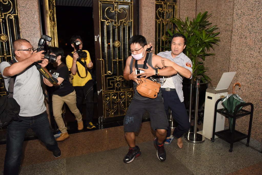 群眾推開教育部建物門後，現場駐警抓著一人，記者廖振輝（左一）、林雨佑（左三）也尾隨拍攝。事後得知當時被抓住者為翁柏恩，主張自身為公民記者。（攝影：宋小海）