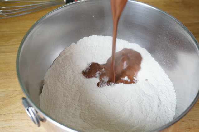 A stream of hot cocoa mixture plunges into a mound of flour