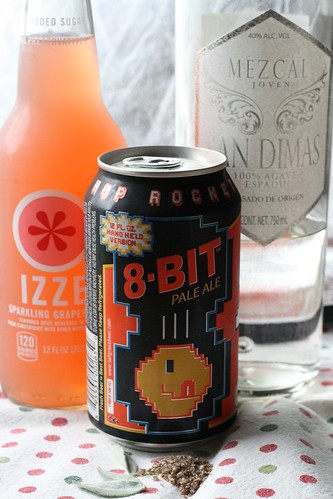 A bottle of Izzie grapfruit soda. A can of 8-Bit Pale Ale. A bottle of mezcal. Sage leaves. Smoked salt.