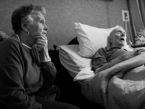 Woman Sits Next To Elderly Man In Bed
