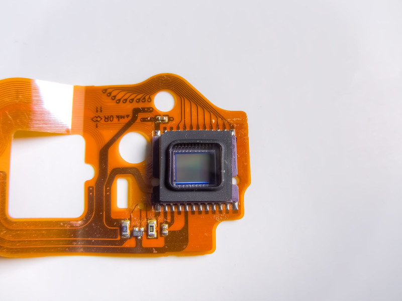 An unadorned sensor on an orange, flat computer ribbon