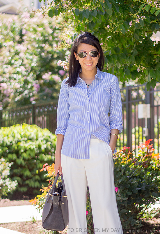 green necklace, blue striped button up shirt, white pants, gray tote