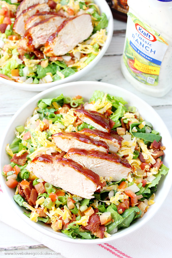 Jacked-Up Monterey Chicken Salad in two bowls with a bottle of salad dressing.