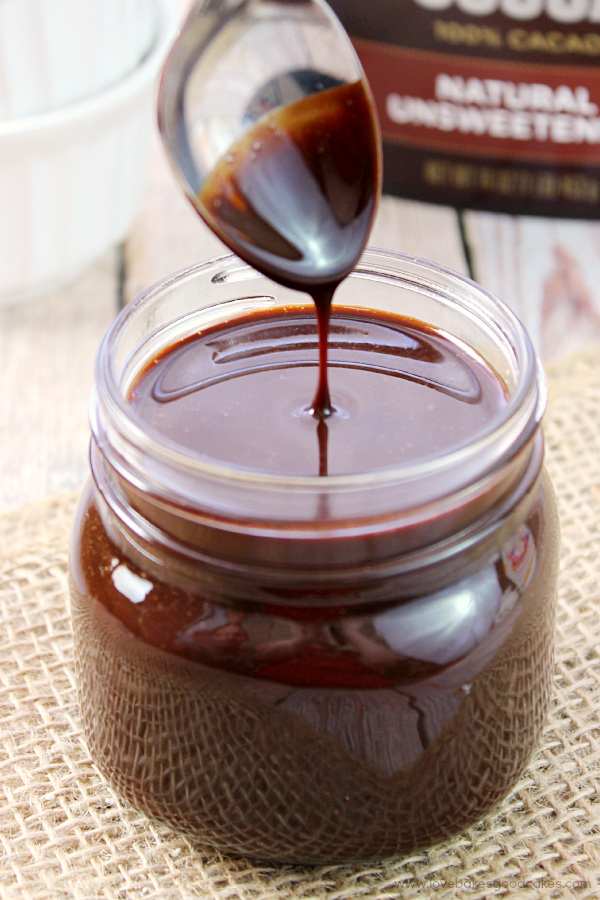 Homemade Chocolate Sauce in a glass jar with a spoon.