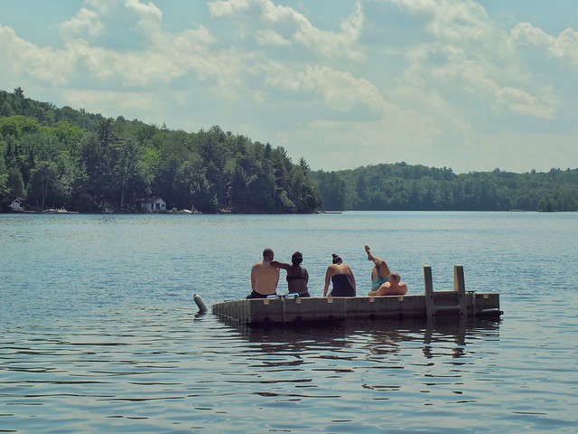 Four people on a raft in a lake with trees in the background