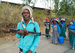 Ethiopian man with a gun and women carrying gifts during an Oromo wedding celebration, Amhara region, Artuma, Ethiopia