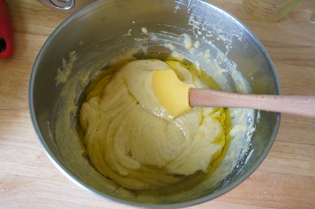 Folding olive oil into the batter, transparent yellow-green against bright canary yellow
