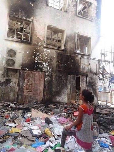 Niña en Yemen frente a un edificio incendiado por los bombardeos