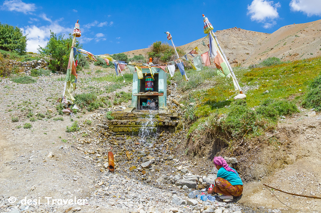 A women filling water from a mountain spring Spiti