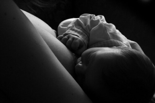foto in bianco e nero di neonato che viene allattato dalla medre