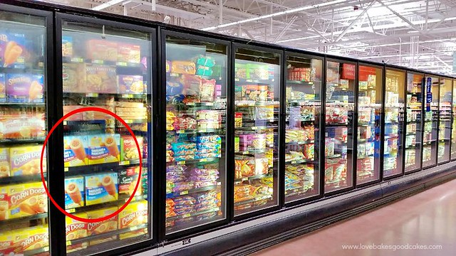 A grocery store isle in the frozen section with products on the shelves.