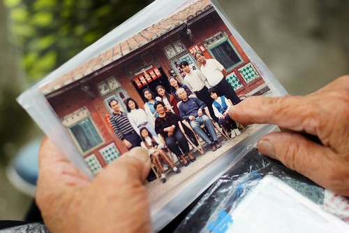 貞妹阿婆指著照片中的家人，說著一段又一段的故事。攝影：李慧宜