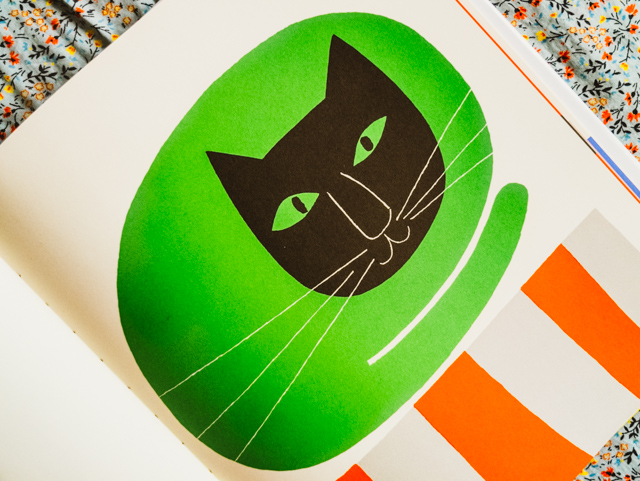 green cat on orange striped rug
