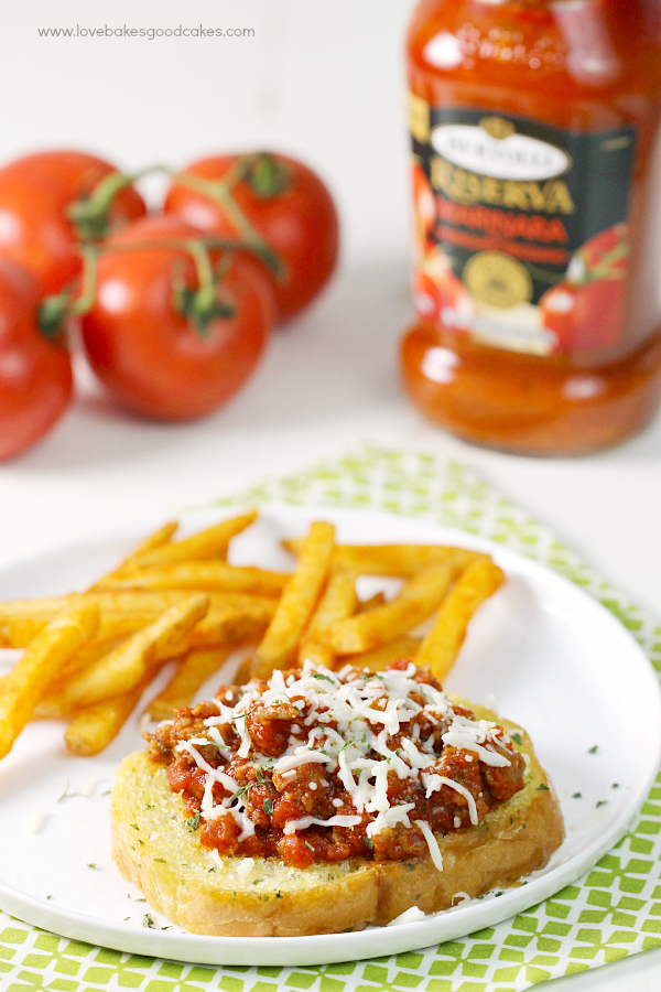 Garlic Bread Italian Sloppy Joes on a plate with french fries and a jar of Bertolli sauce and tomatoes.