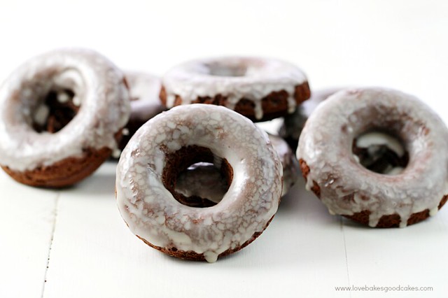 Glazed Chocolate Donuts stacked up on a cutting board.