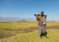 Artuma tribe man in a field with a gun, Amhara region, Kemise, Ethiopia