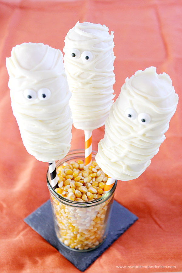 Mummy Twinkie Pops in a glass of popcorn kernels.
