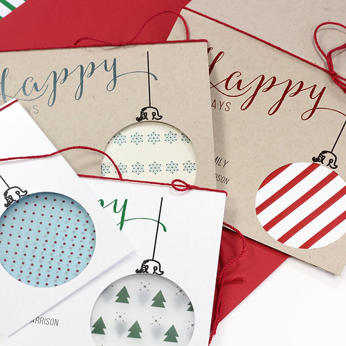 four printed cutout ornament holiday cards, each one with a different patterned paper showing from inside cutout
