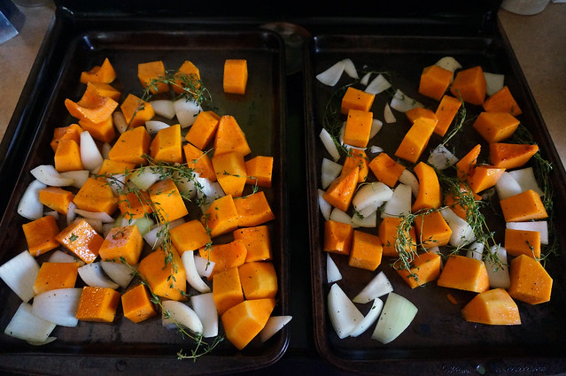 Anticipation: two baking sheets, side by side, covered in chunks of butternut squash and onion, with sprigs of thyme scattered throughout, all ready for the oven