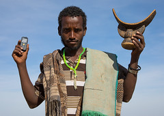 Issa tribe man holding a mobile phone and a wooden pillow, Afar region, Yangudi Rassa National Park, Ethiopia