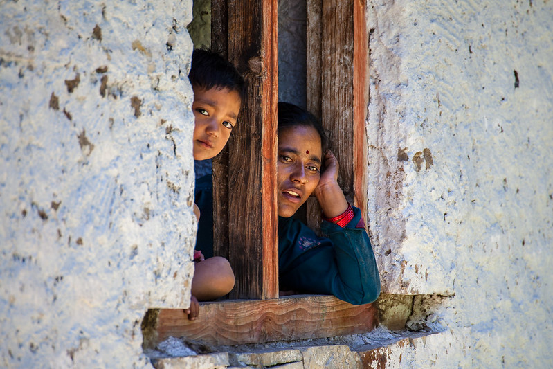 Woman and boy looking out of a window, Nepal
