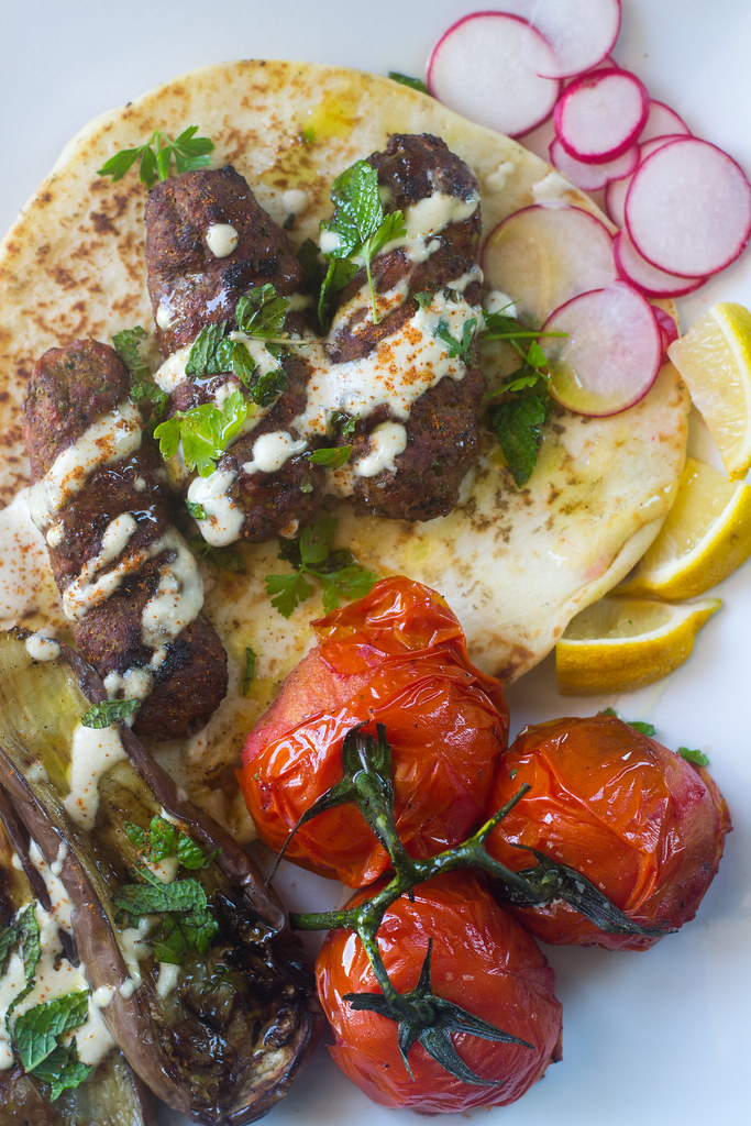 Middle Eastern grill with grilled kofta, eggplant and tomatoes all drizzled with garlicky tahini sauce.