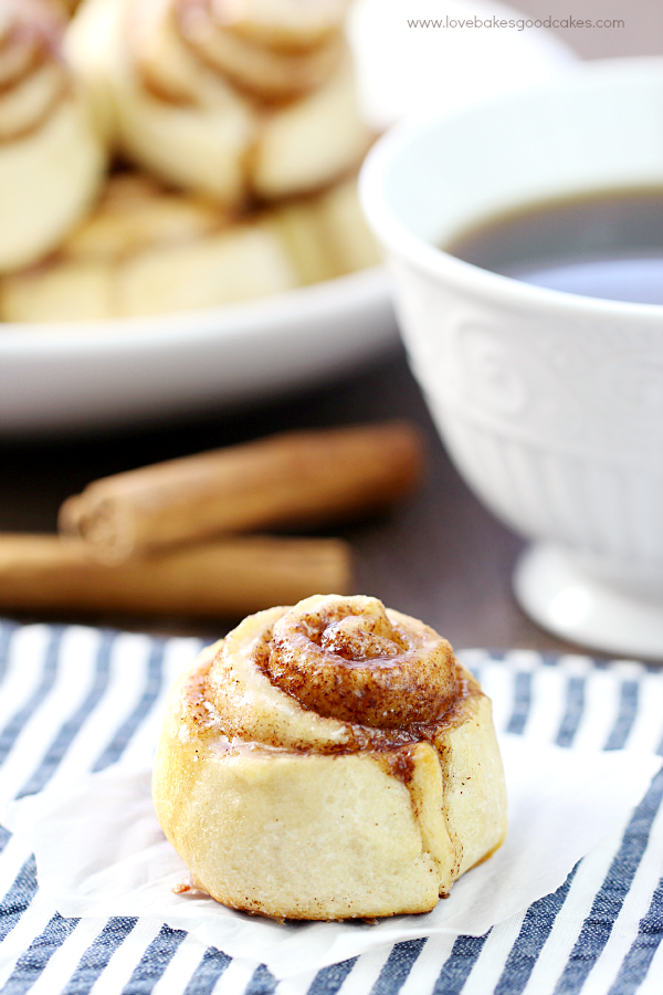 Quick & Easy Cinnamon Roll on parchment paper with a cup of coffee.