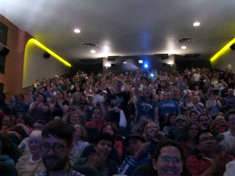 Fans cheering in a darkened movie theater