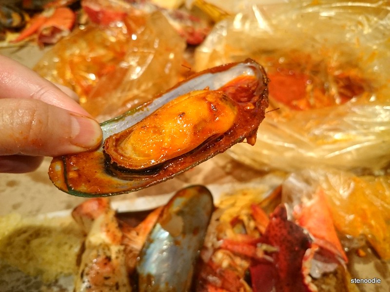hand holding mussel in seafood boil