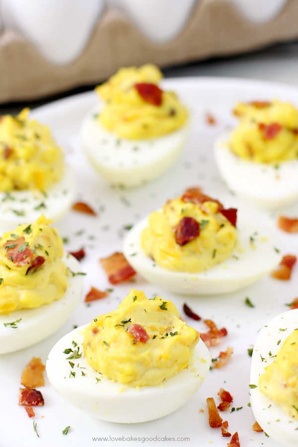 Bacon Cheddar Deviled Eggs on a plate with bacon pieces.
