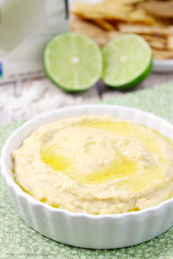 Tropical Hummus in a white bowl with two limes.