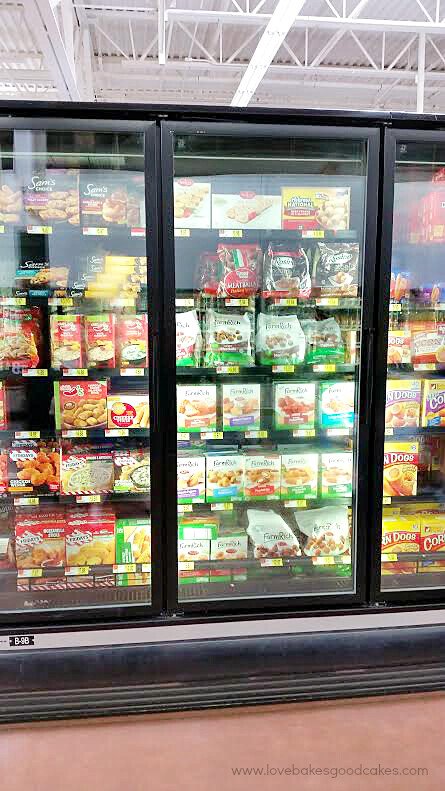 A grocery store isle in the frozen section with products on the shelves.