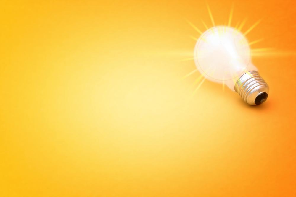 glowing white light bulb against bright yellow background