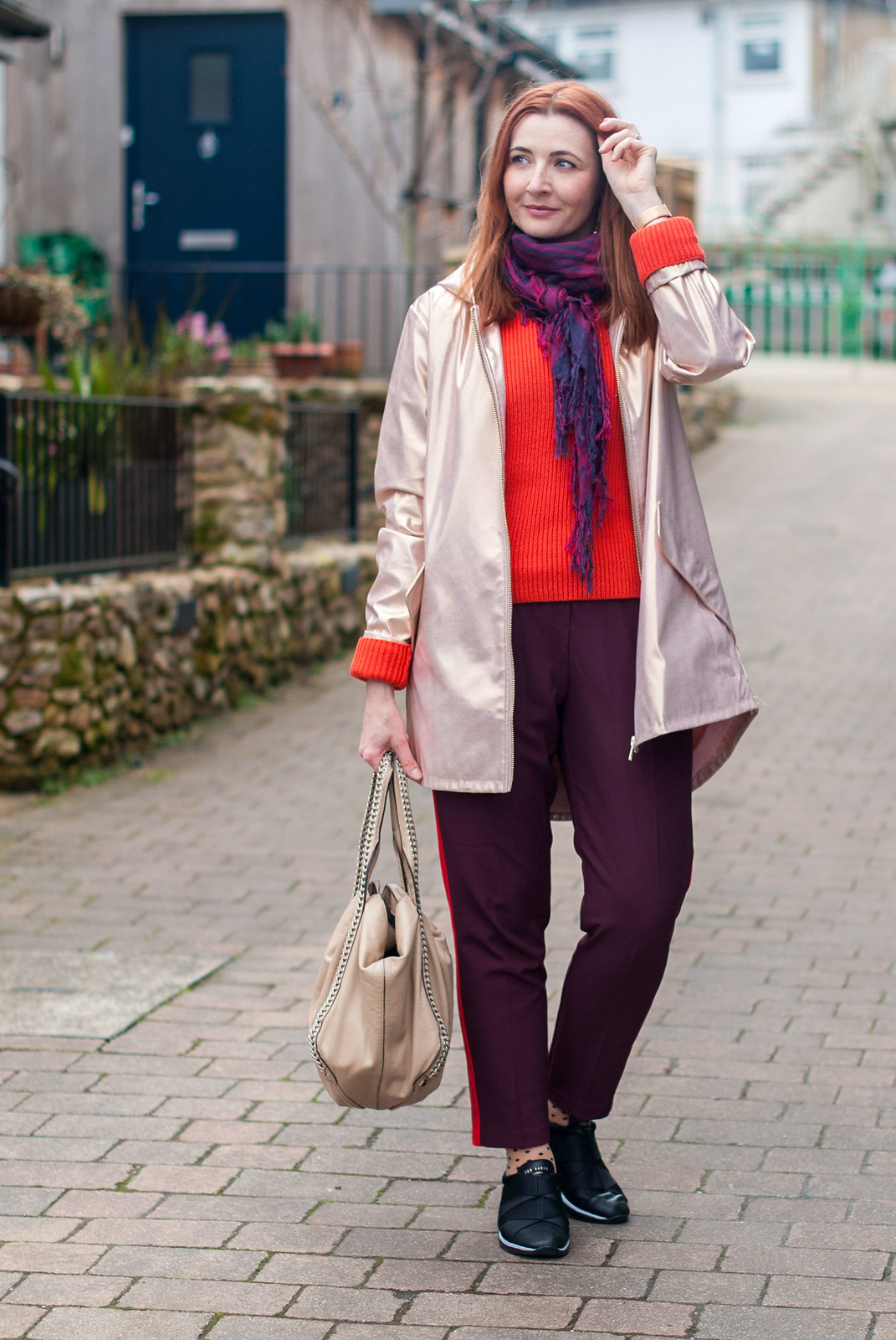 Beating April Showers in Metallics and Warm Colours \ rose gold raincoat \ orange-red sweater \ burgundy and red stripe trousers pants \ Ted Baker Queane trainers sneakers \ polka dot socks | Not Dressed As Lamb, over 40 style