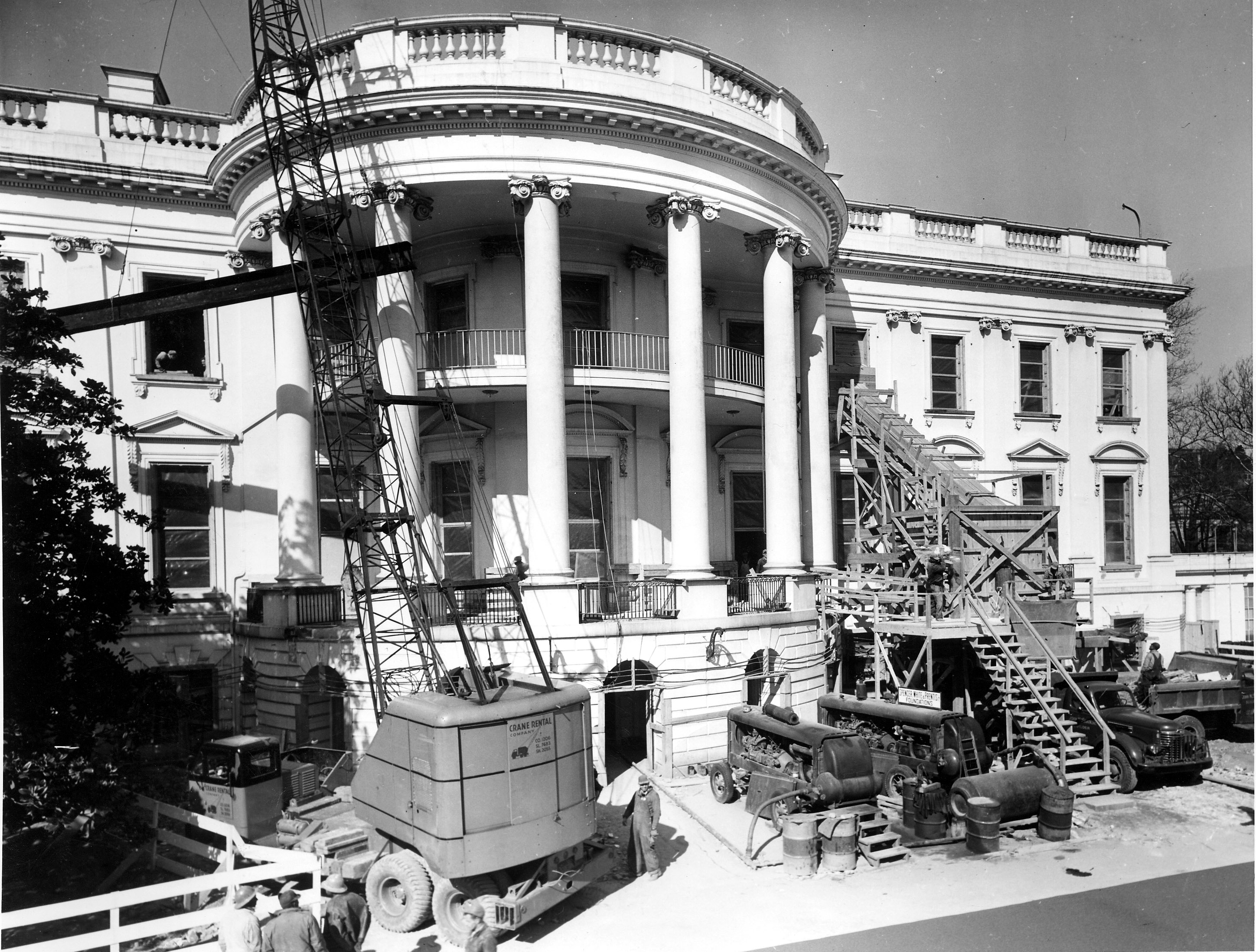 Removing debris from the renovation of the White House, on February 27, 1950. On the left, a truck crane is lifting a 40-foot beam through the southwest window of Room 20 on the second floor of the White House. On the right, debris from the hopper is being loaded on a truck. Photo from the holdings of the National Archives and Records Administration, cataloged under the National Archives Identifier (NAID) 6982091. 