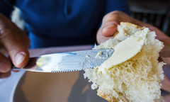 Hand spreading butter onto a piece of bread