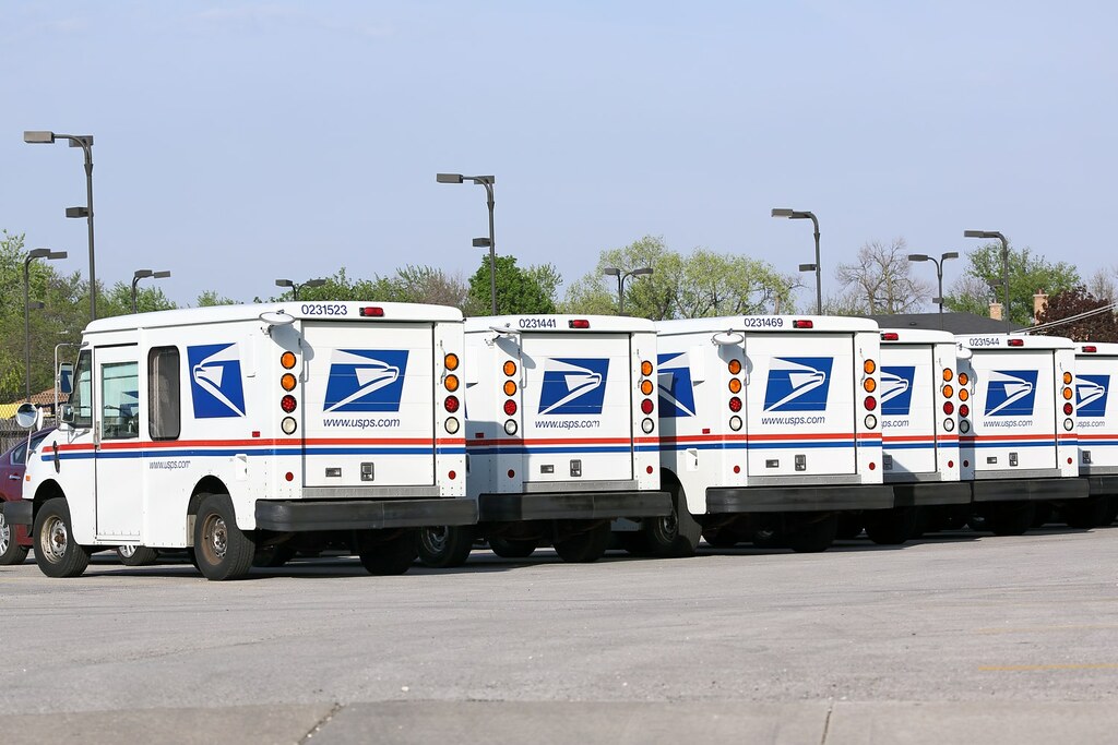 White mail vans bearing the logo of the United States Postal Service.