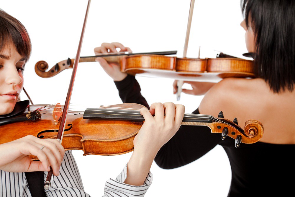 photo of two women playing violins