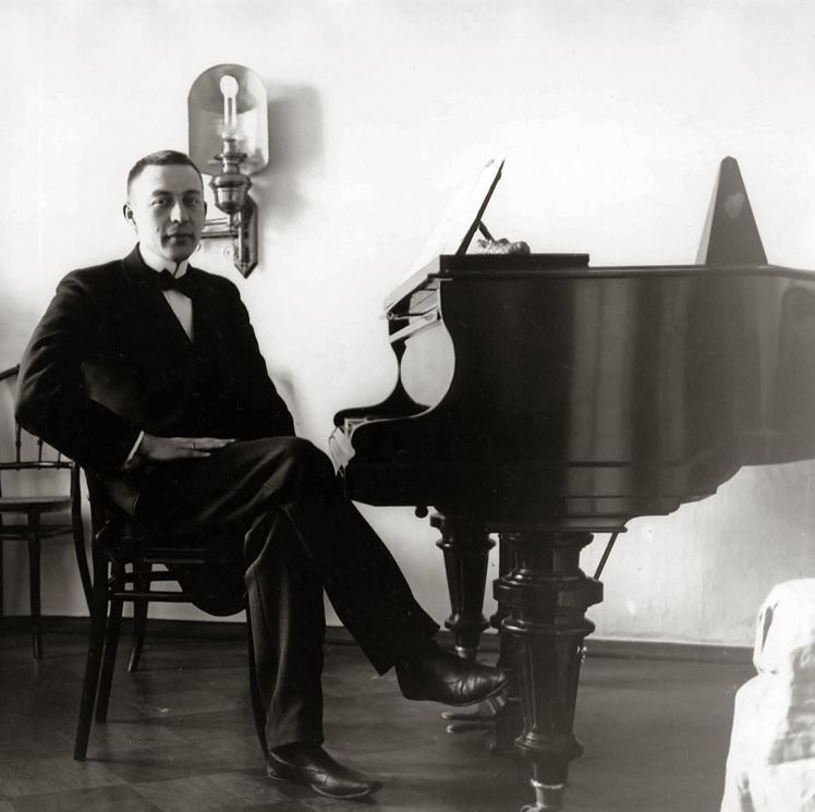 Sergei Rachmaninoff sitting beside a grand piano