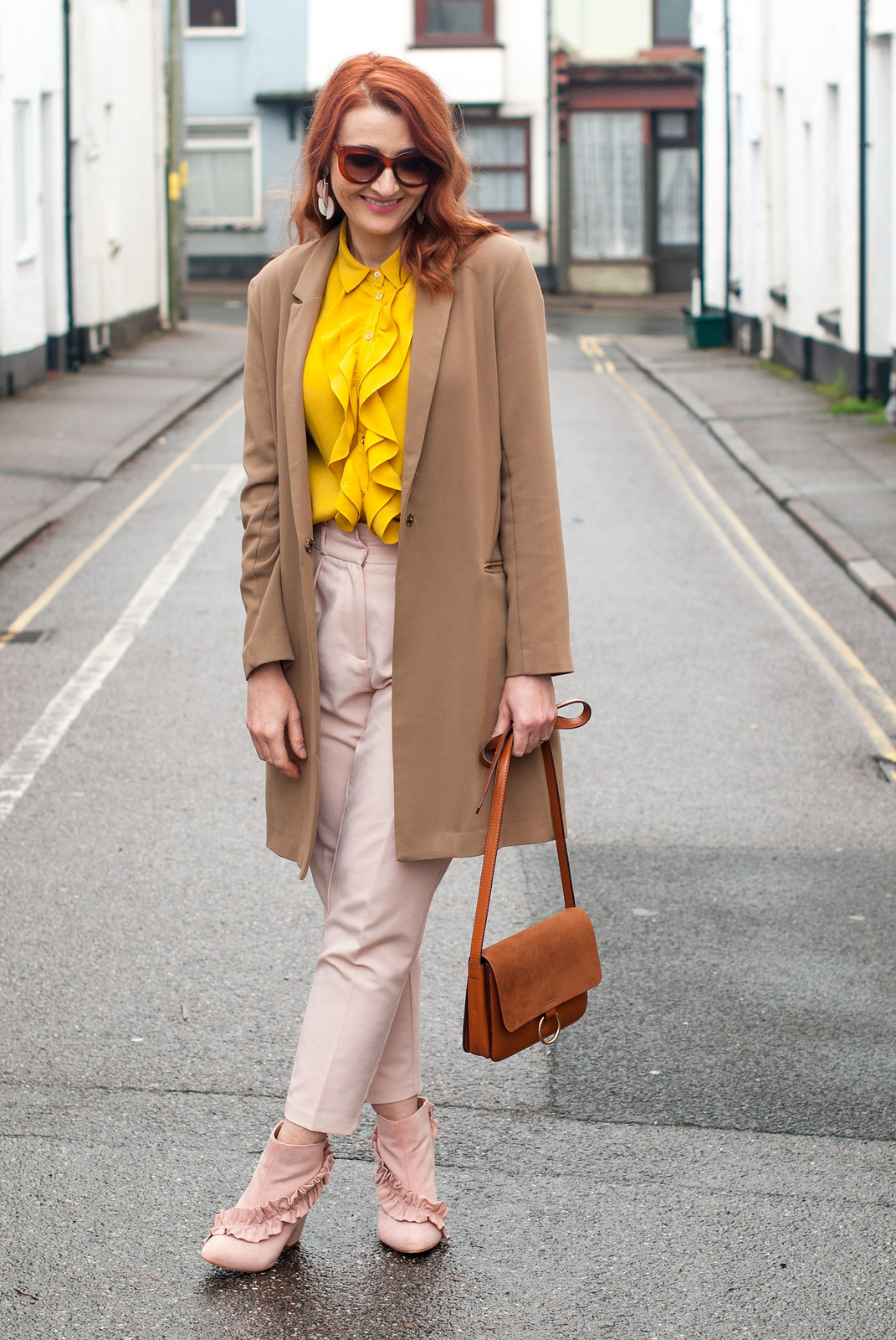 Easter outfit of pastels: Ruffled yellow blouse \ longline camel blazer \ pastel pink peg leg trousers \ tapered pants \ pink ruffle ankle boots | Not Dressed As Lamb, over 40 style